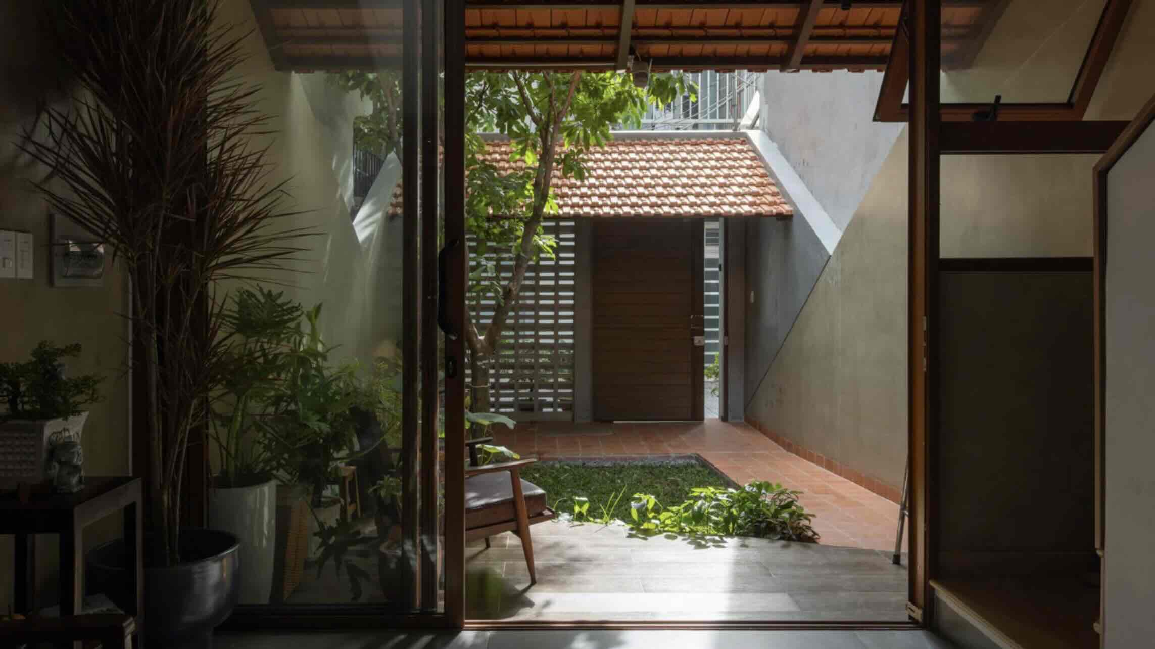 Mái nhà lợp ngói đất nung ôm lấy ngôi nhà mái hẹp ở Việt Nam do Trung Nguyên Architects thiết kế.